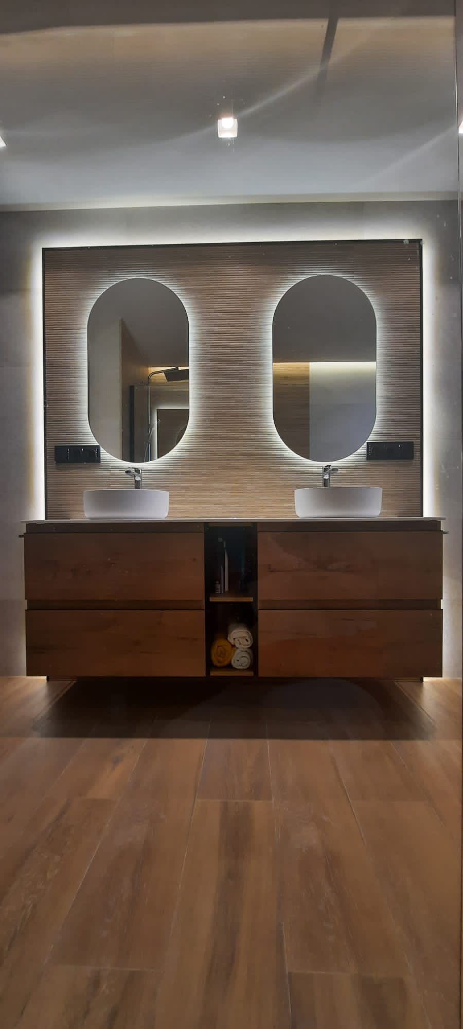 Baño doble con espejos iluminados y azulejo texturizado