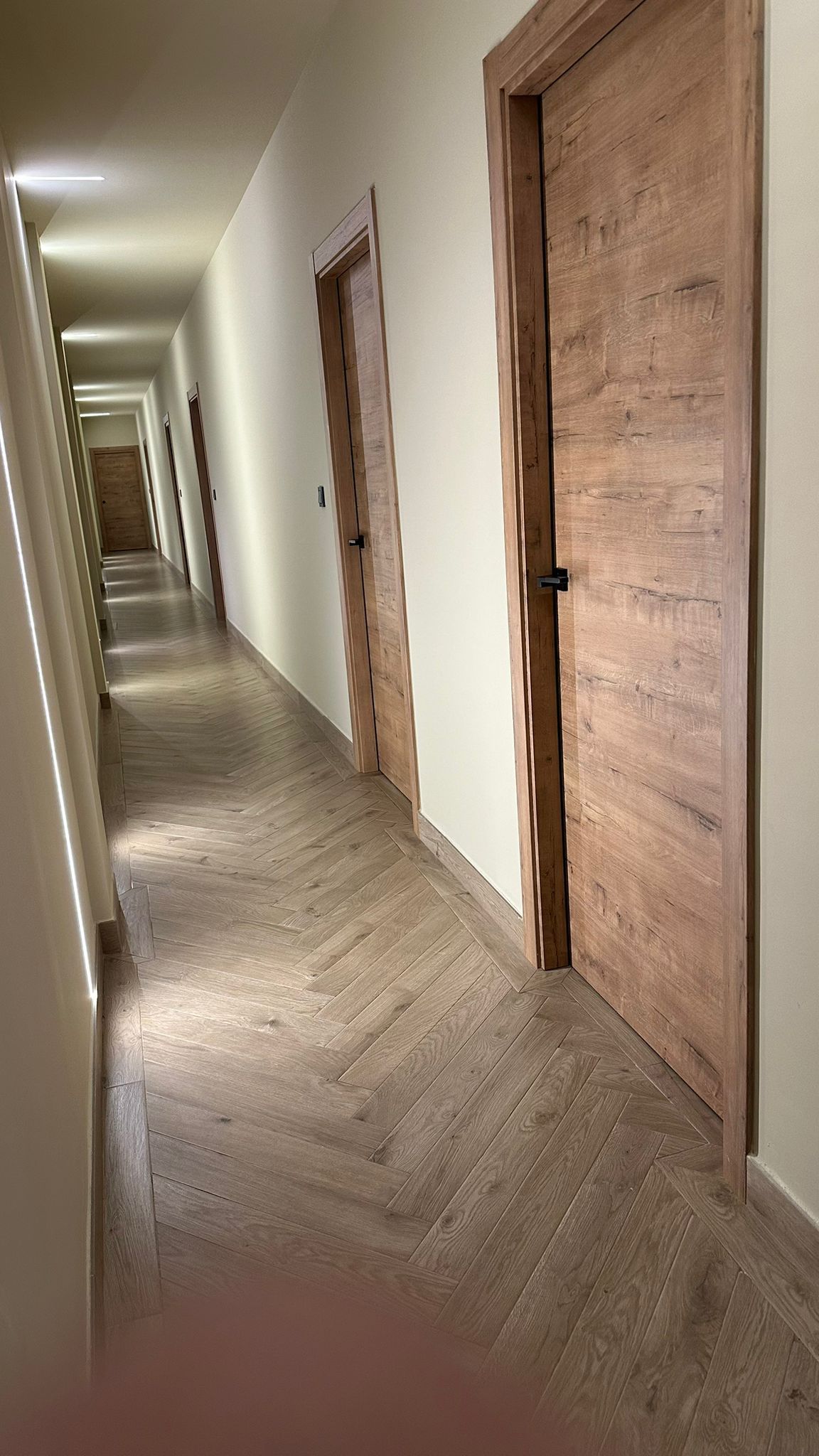 Pasillo elegante con pavimento porcelánico efecto madera en patrón de espiga