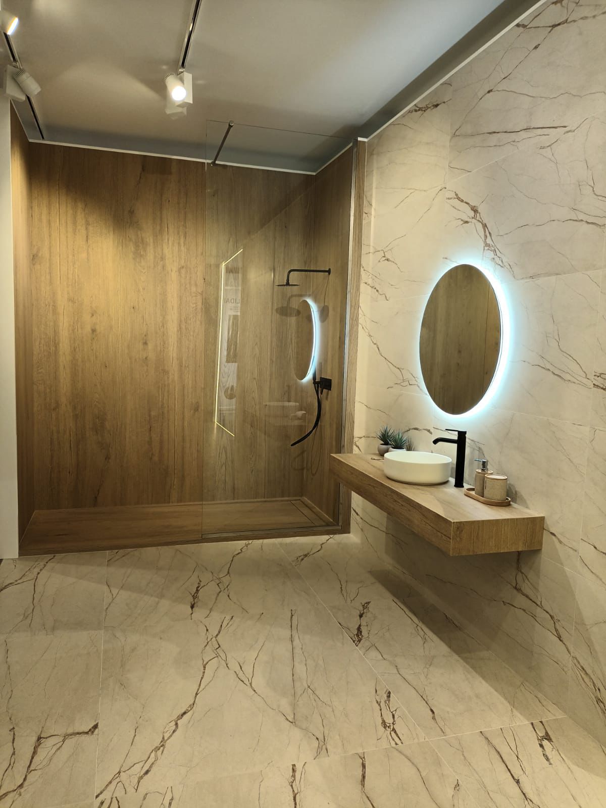 Baño de diseño con revestimiento efecto mármol y zona de ducha en porcelánico imitación madera