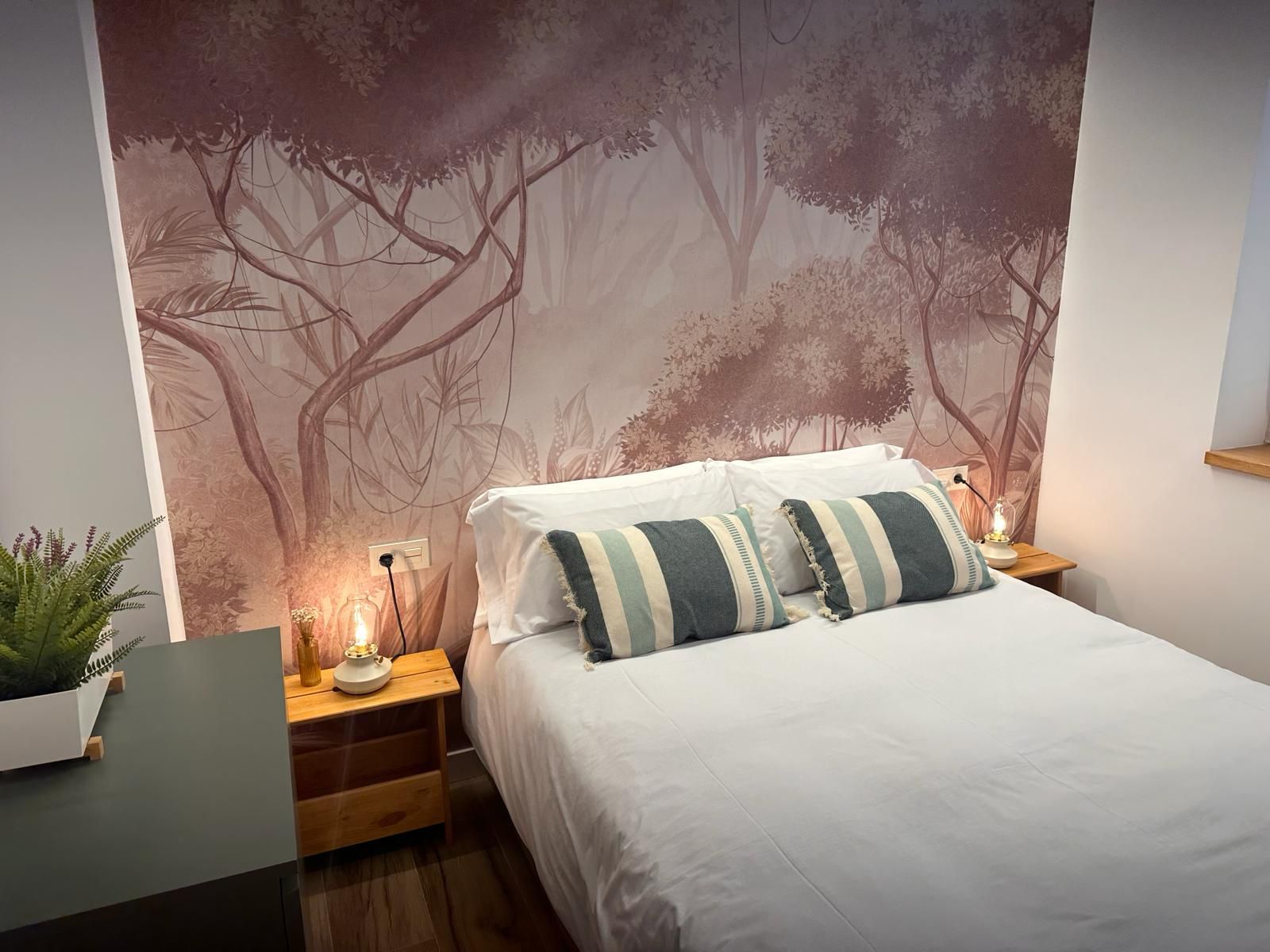 Dormitorio principal con suelo de madera y mural tropical