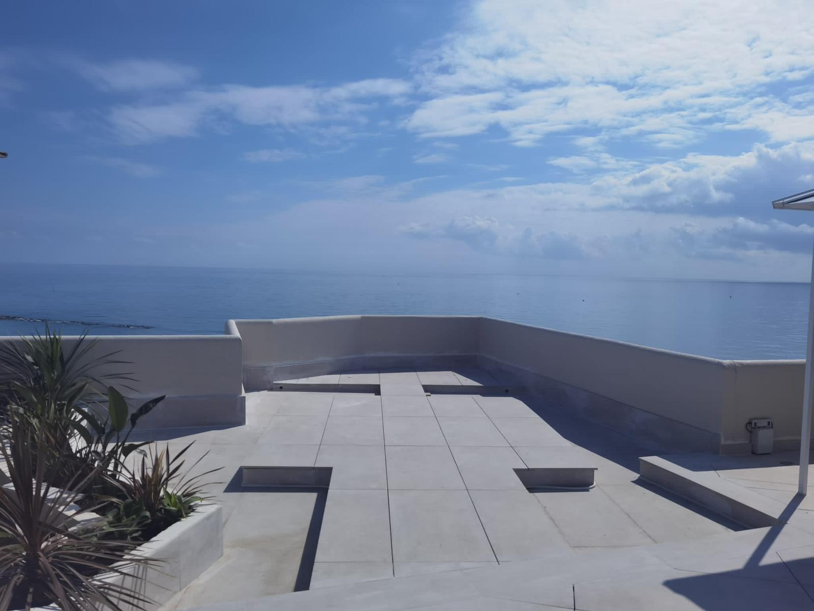 Terraza azotea con vistas al mar pavimentada con porcelánico gris de gran formato