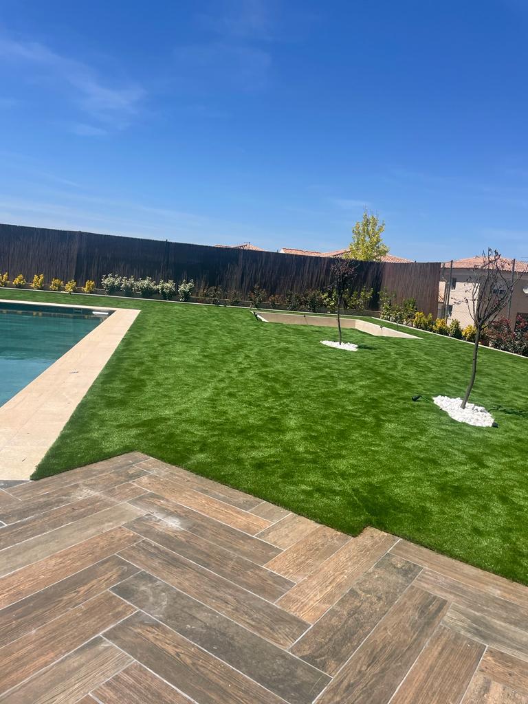 Exclusivo entorno de piscina con pavimento porcelánico efecto madera en espiga y césped