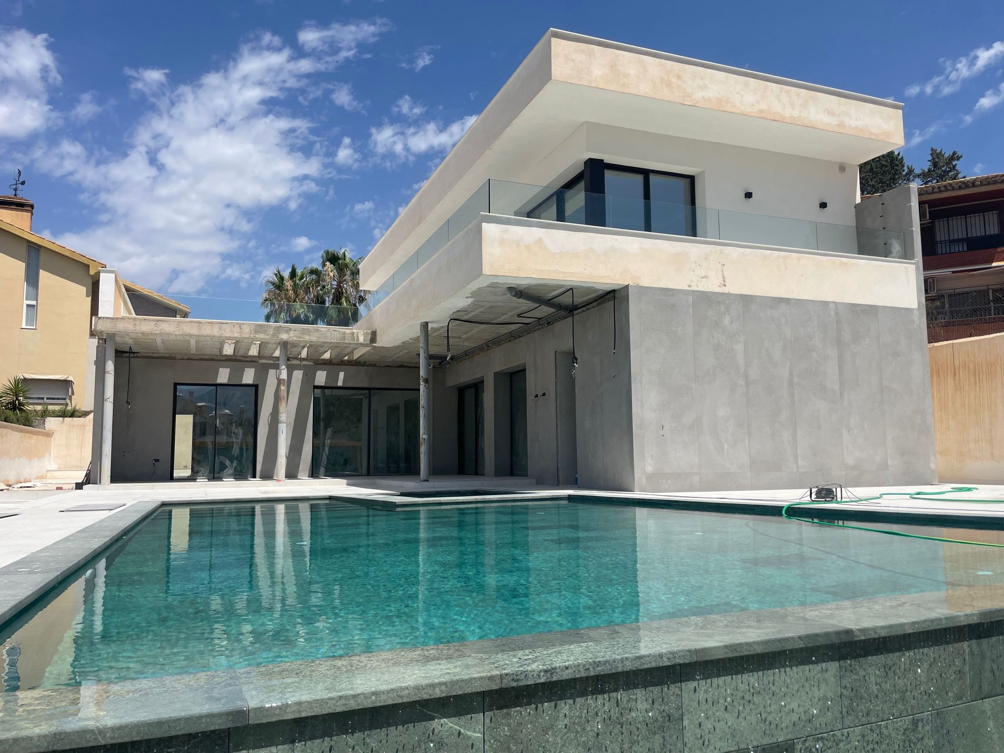 Exterior de villa moderna con piscina y terraza gris