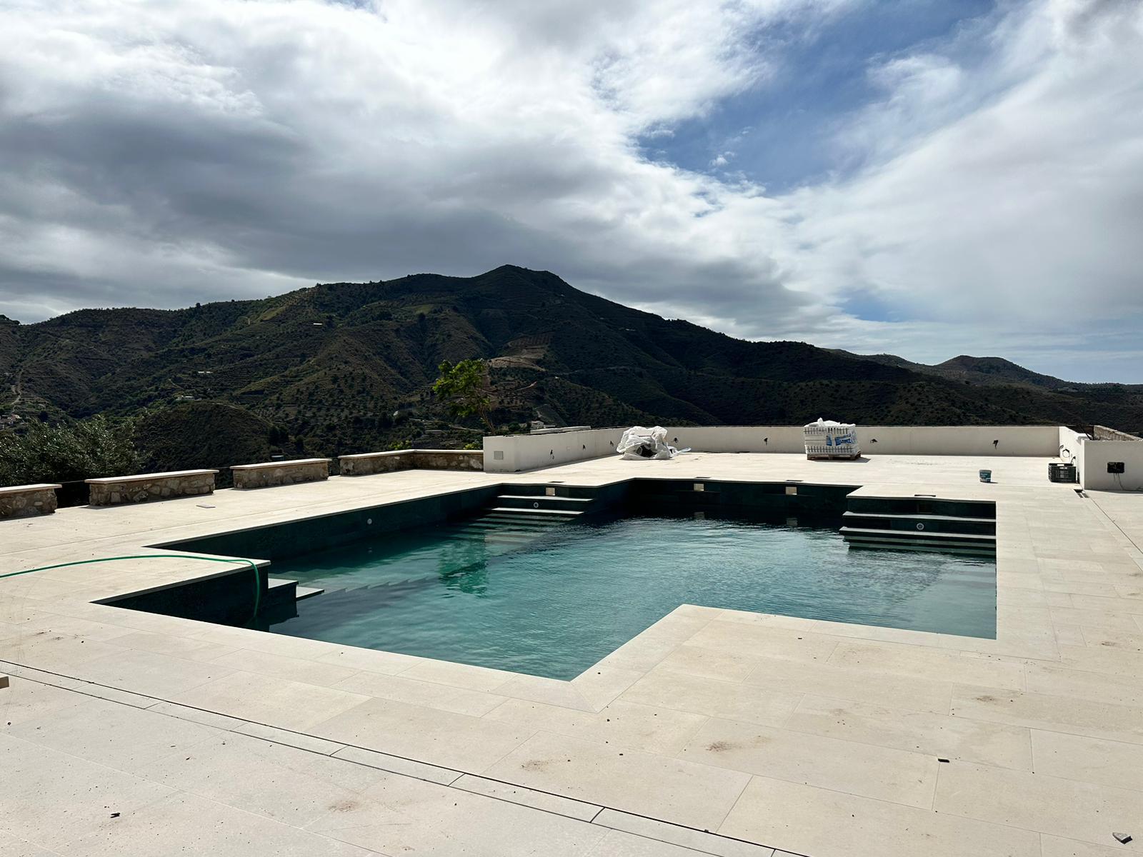Piscina infinita con vistas a la montaña y suelo claro