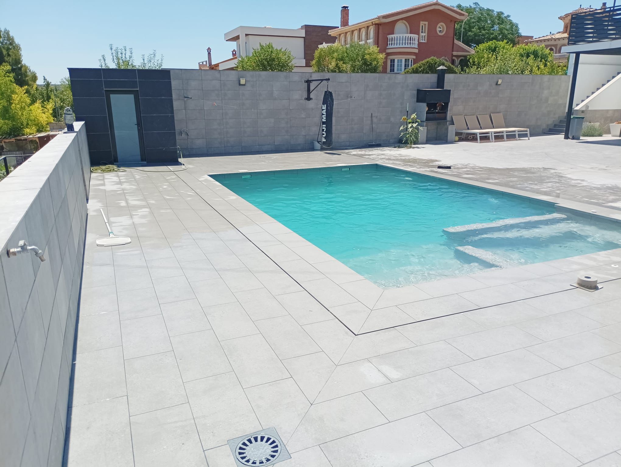 Zona de piscina con revestimiento gris y saco de boxeo