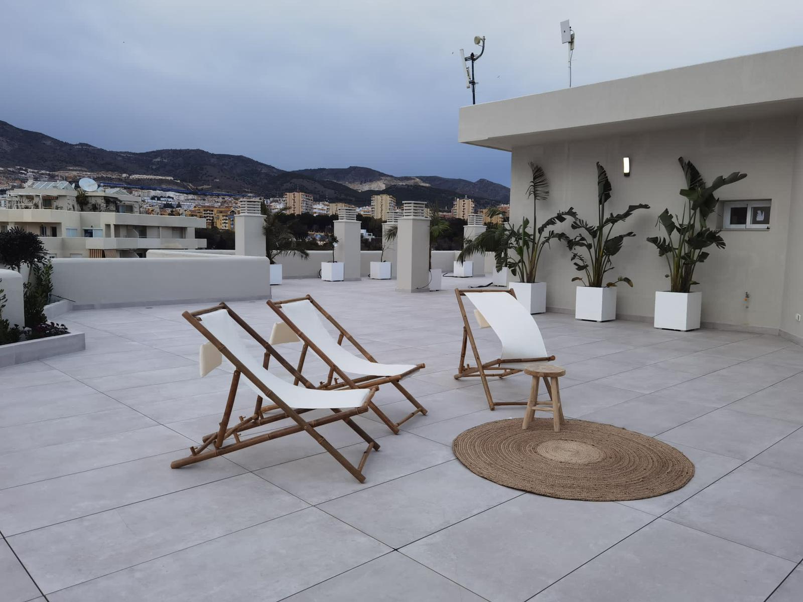 Solárium en azotea con sillas de bambú y suelo gris