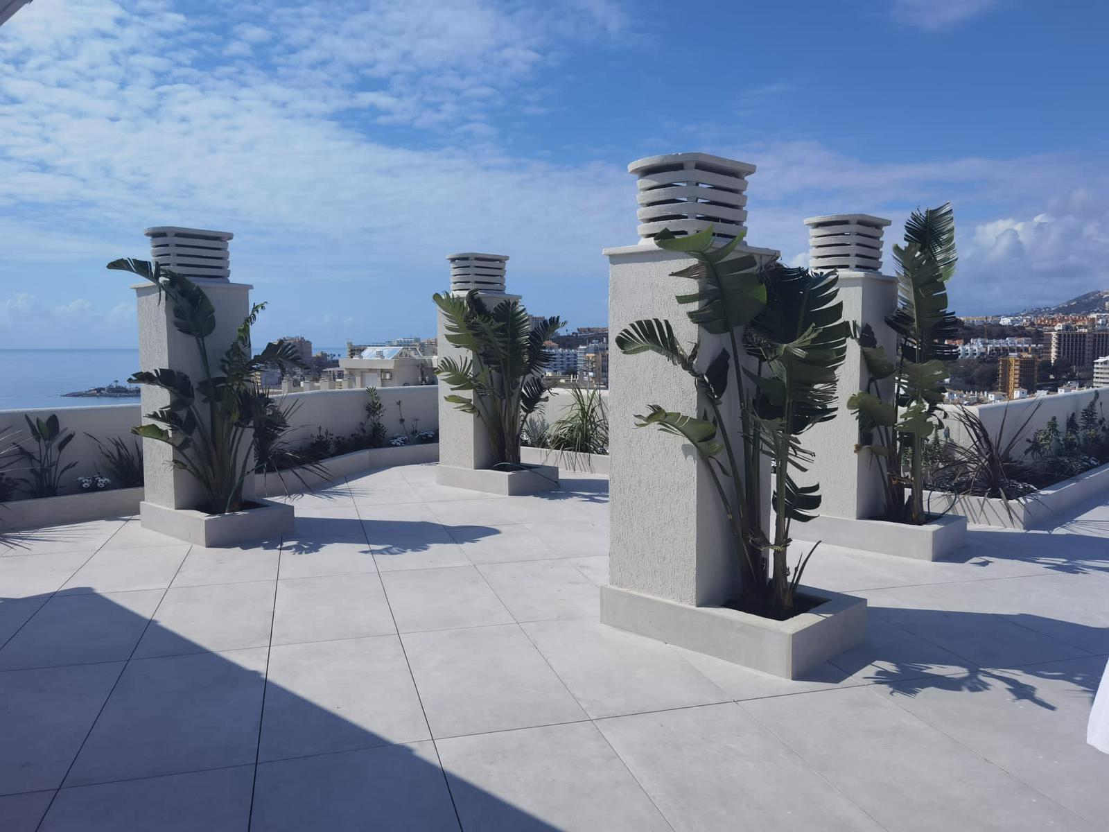 Terraza con maceteros blancos y plantas tropicales